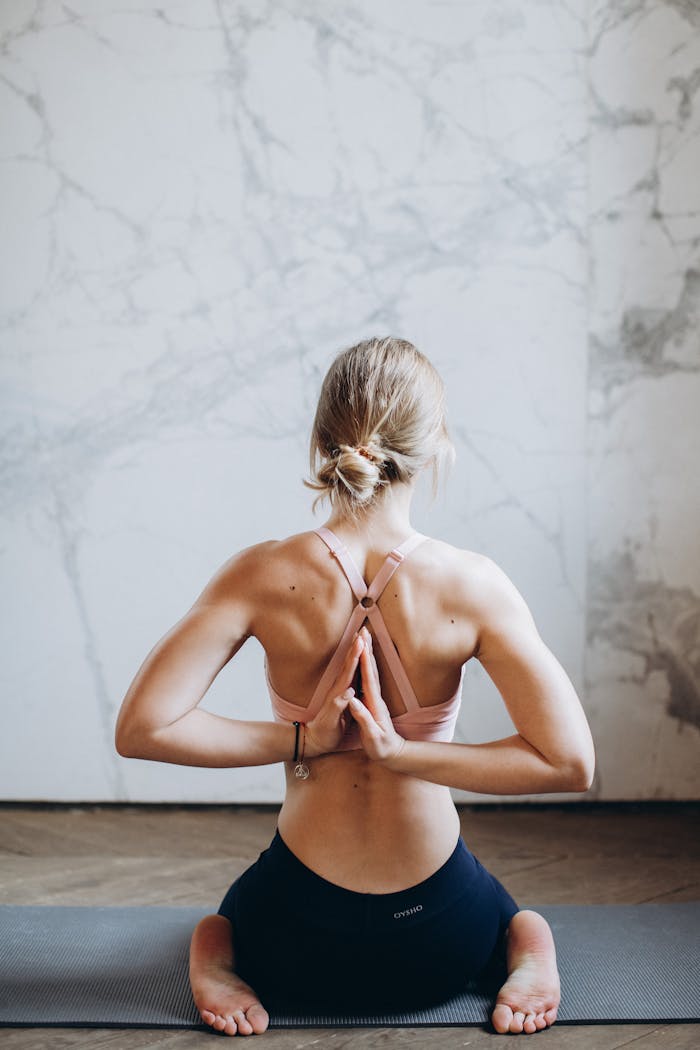 A young woman meditating indoors in reverse prayer pose, enhancing wellness and mindfulness.