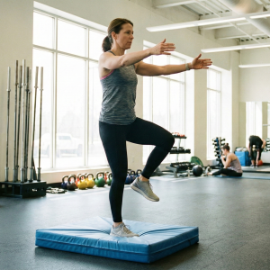 Person doing balance drills on a foam pad to improve stability and coordination in a gym setting.