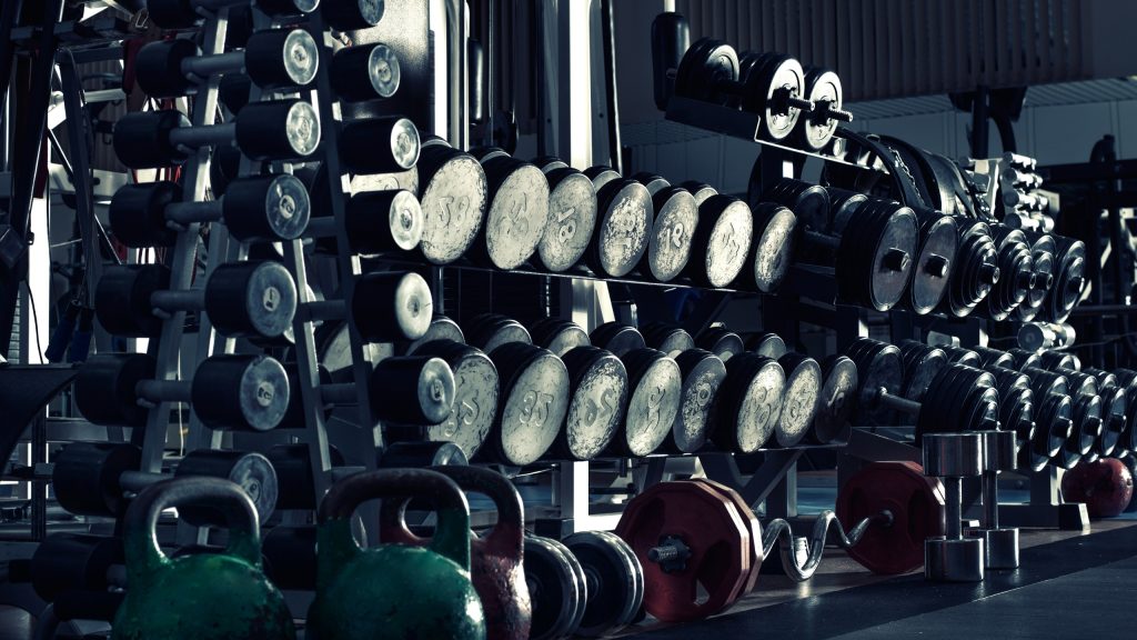 Dumbbell rack displaying progressive weight options for drop set training technique implementation in professional gym setting